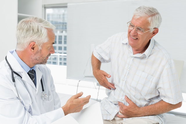 Anciano en el médico con dolor en el abdomen.