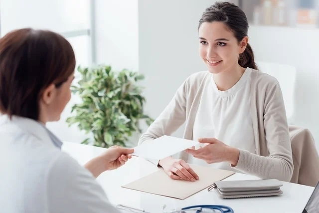 Mujer joven en una oficina recibiendo una receta médica del ginecólogo