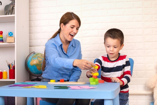 Niño jugando en una mesa con un terapeuta ocupacional